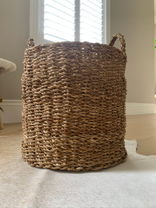 A brown woven basket in front of a window.