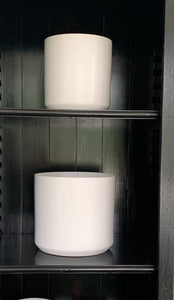 Matte white ceramic pots on black painted shelves.