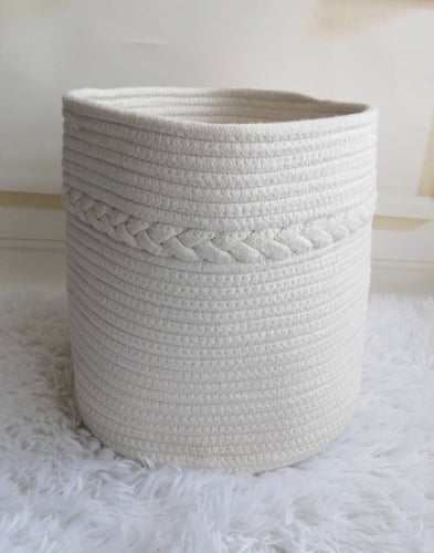 A white rope basket on a rug in front of a white rope basket.
